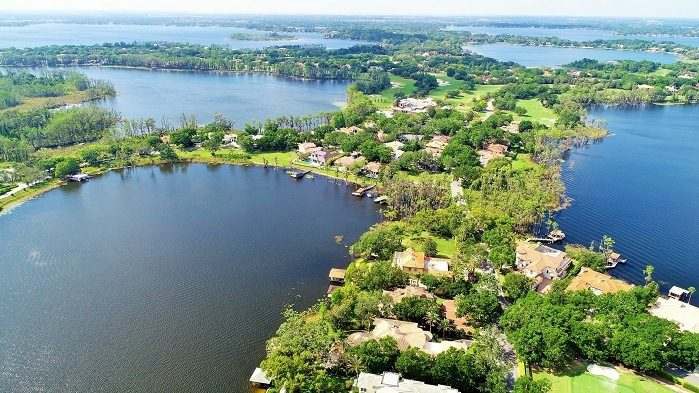 Vista aérea de lagos de Windermere ligados entre si, com casas e trapiches na faixa de terra arborizada entre a água